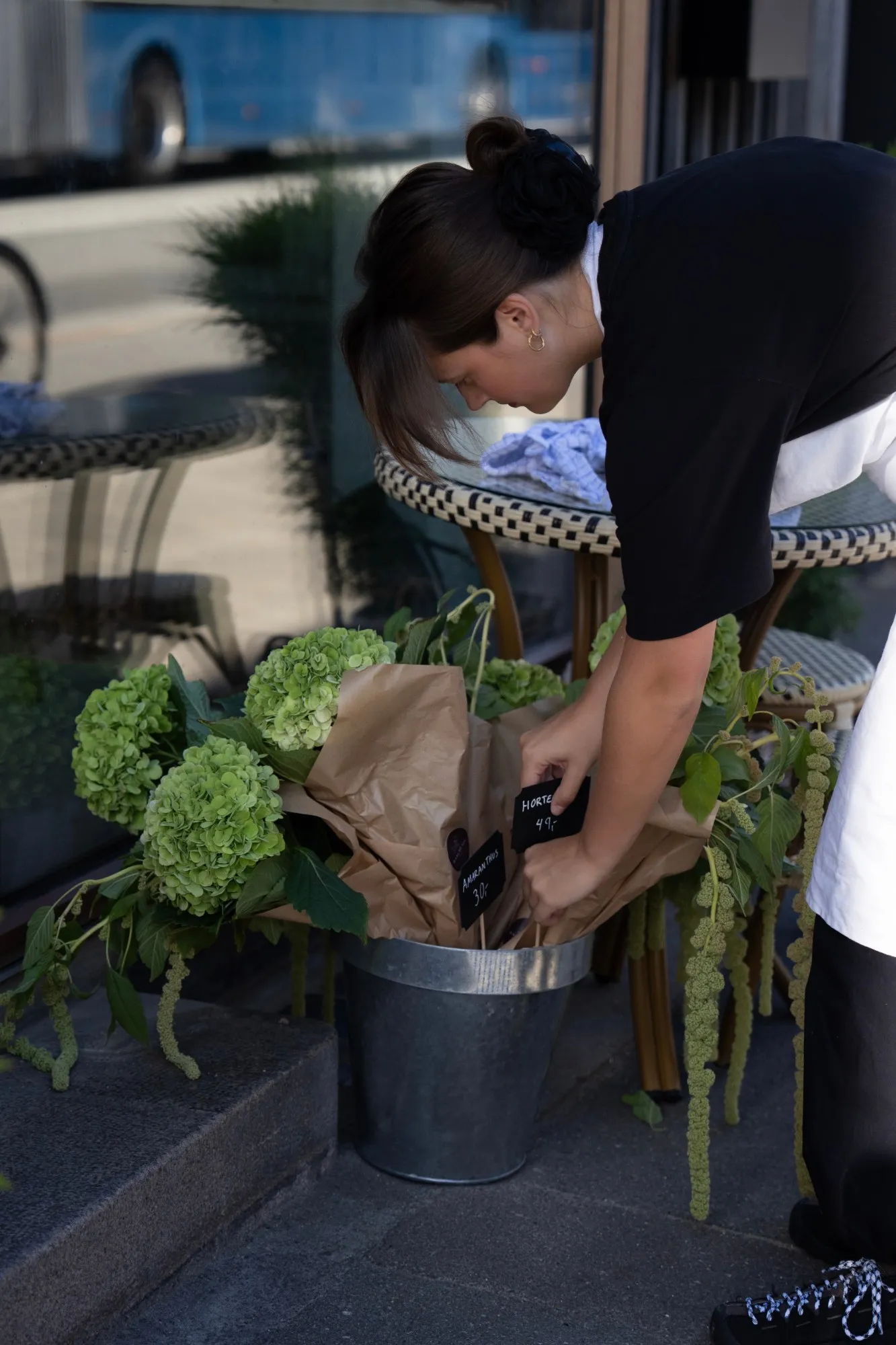Hortensia og amaranthus i brunt papir bliver sat i en zinkspand foran butikken, med håndskrevne prisskilte
