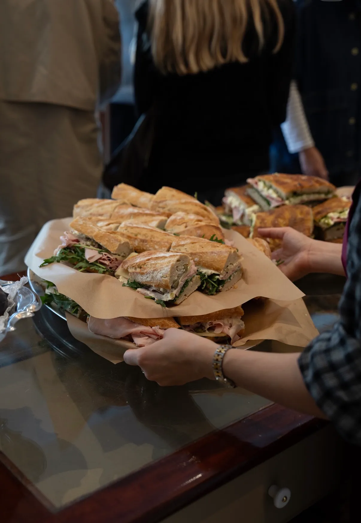 Et fad med frisklavede baguettesandwiches med skinke, ost og rucola